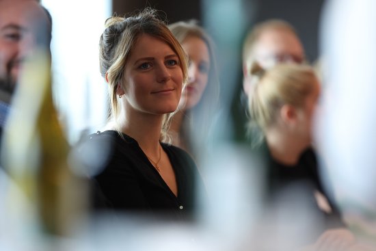 Nadine Richter, a young woman with her blonde hair pinned up, is wearing a black top and smiling slightly in a group meeting.