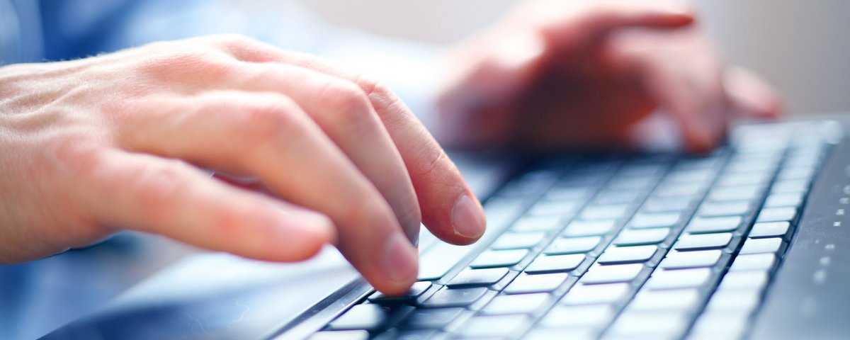 Hands typing on a black computer keyboard in close-up